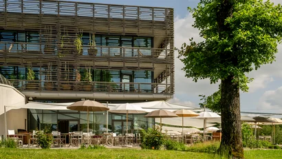 Außenbereich mit Sonnenschirmen und Sitzplätzen vor modernem Gebäude