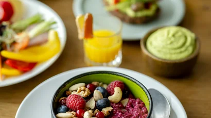 Schüssel mit Beerenmüsli und Nüssen auf weißem Teller mit Löffel