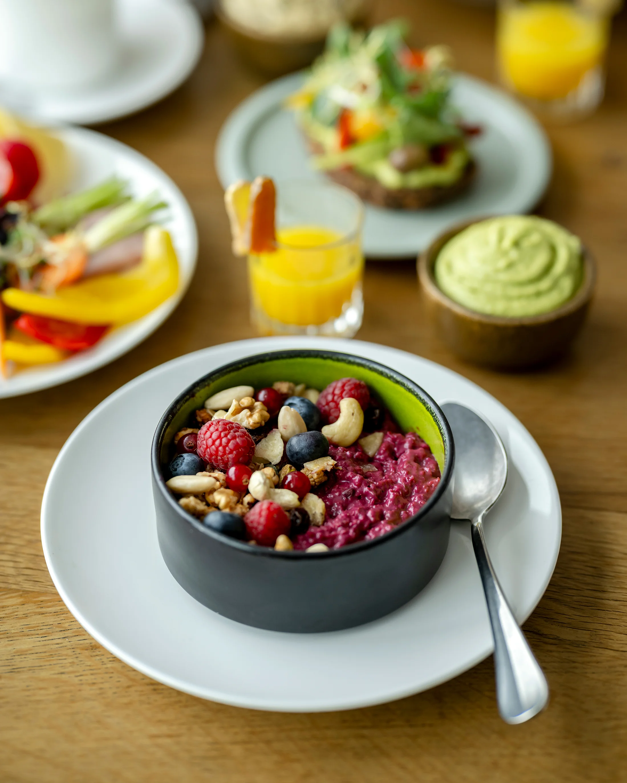 Schüssel mit Beerenmüsli und Nüssen auf weißem Teller mit Löffel