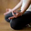 Person sitzt im Schneidersitz und meditiert mit Hand in Mudra-Position