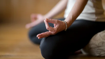 Person sitzt im Schneidersitz und meditiert mit Hand in Mudra-Position