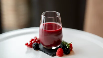 Glas mit rotem Beerensaft und Beeren auf weißem Tisch