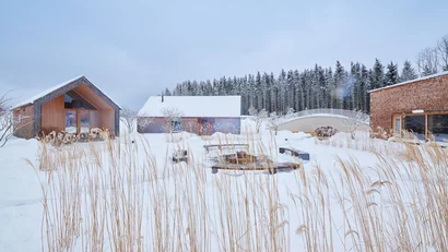 Verschneite moderne Häuser mit Holzfassade in winterlicher Landschaft
