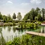 Natürlicher Schwimmteich mit Liegestühlen, Pavillons und grüner Landschaft