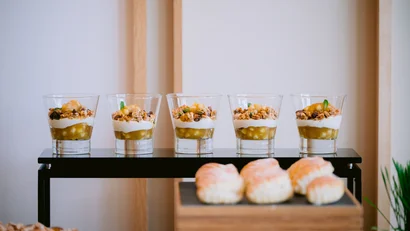 Fünf Gläser mit Joghurt, Früchten und Müsli auf einem schwarzen Tisch