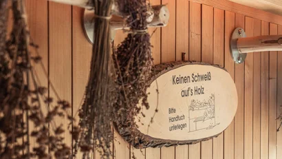 Getrocknete Kräuter hängen in einer Sauna mit Holzverkleidung und einem Schild