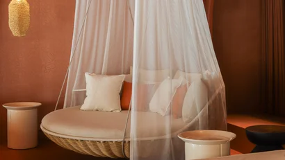 Gemütliche Hängesitzbank mit Moskitonetz und warmen Lampen in orangefarbener Umgebung