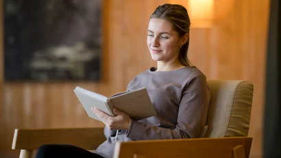 Frau entspannt lesend in einem gemütlichen Sessel