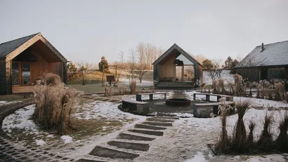 Moderne Holzhäuser mit Sitzkreis und leichter Schneebedeckung im Garten
