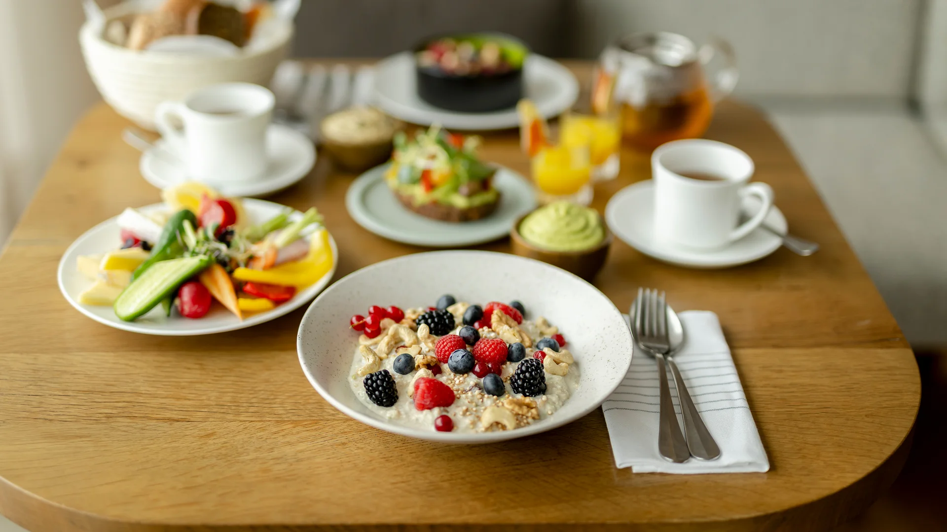 Verschiedene Frühstücksgerichte mit Früchten, Nüssen und Getränken auf Holztisch