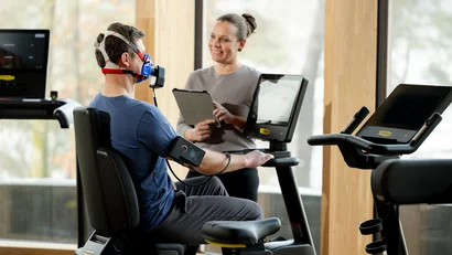 Mann macht Belastungstest mit Maske und Trainerin beobachtet