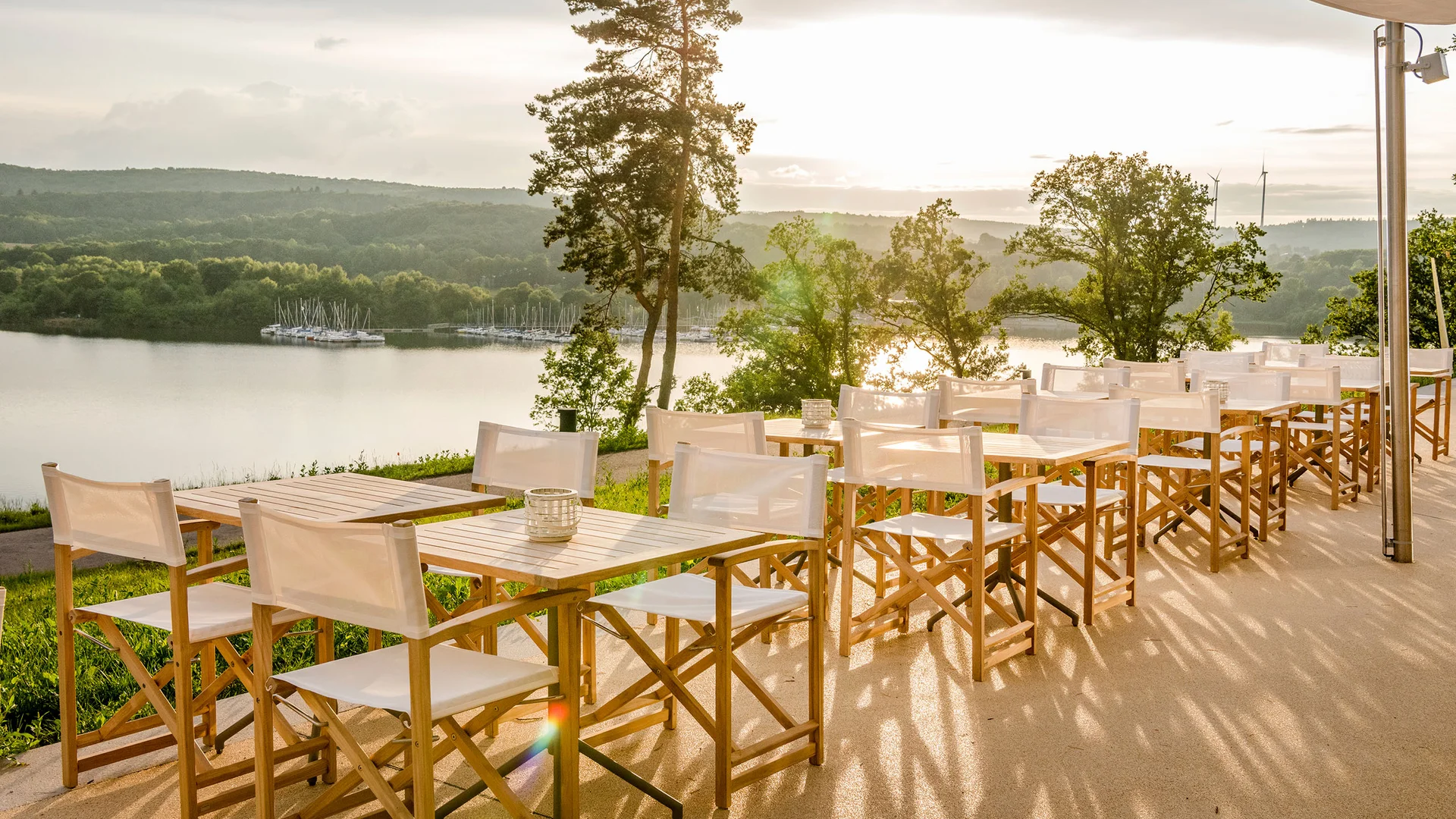 Leere Außenterrasse mit Blick auf See und Hügel im Sonnenuntergang