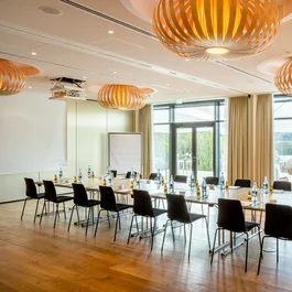Moderner Konferenzraum mit U-förmigen Tischen und Blick auf Terrasse und Natur