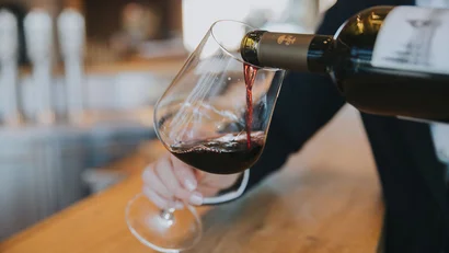 Rotwein wird in einem Weinglas an einer Bar eingeschenkt