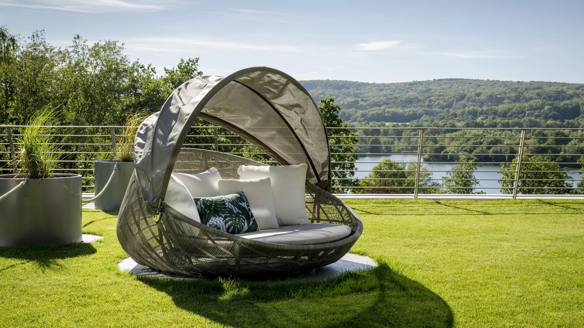 Moderner Garten-Loungesessel mit Dach auf Rasen vor See und Wald