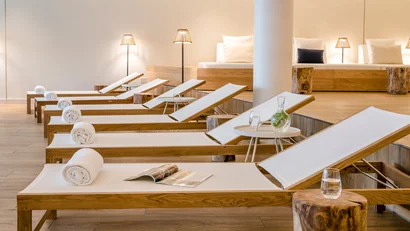 Reihen von Liegestühlen mit weißen Polstern und Handtüchern in einem Wellnessbereich