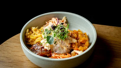 Schüssel mit Reis, Gemüse, Sprossen und Soße auf Holzuntergrund