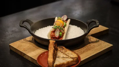 Gourmetgericht mit rohem Ei und geröstetem Brot auf Holztisch