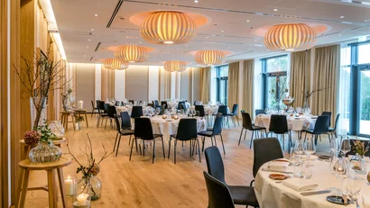 Eleganter Bankettsaal mit gedeckten Tischen und modernen Lampen