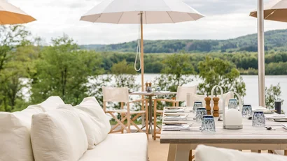 Elegante Außenterrasse mit gedecktem Tisch und Blick auf See und grüne Landschaft