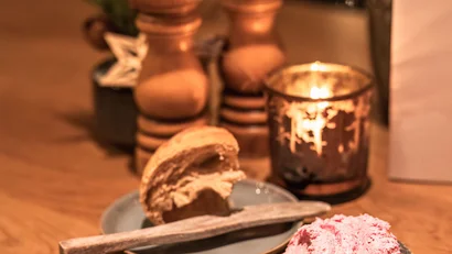 Gemütlicher Tisch mit Brot, Butter, Kerze und Pfeffermühlen im Restaurant