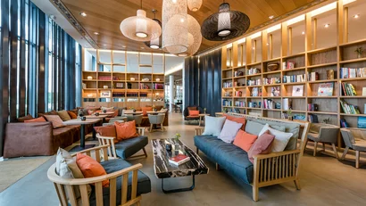Gemütlicher moderner Leseraum mit Bücherregalen, Sitzecken und dekorativen Lampen