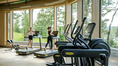 Fitnessraum mit Fenster und zwei Frauen laufen auf Laufbändern