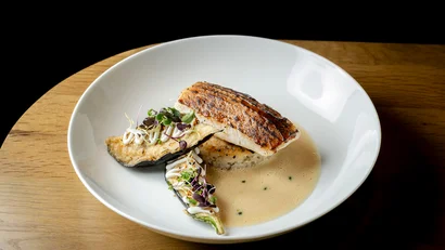 Gegrilltes Fischfilet mit Reis, Auberginen und Soße auf weißem Teller