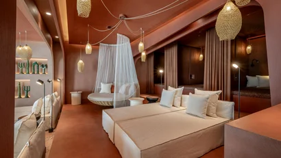 Modernes Schlafzimmer mit Doppelbett, Hängesessel und warmen Pendelleuchten