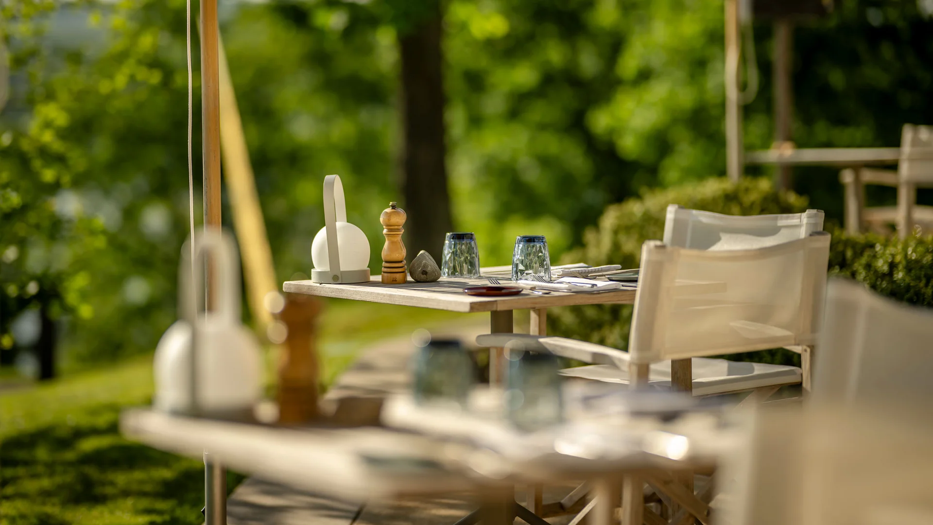 Leerer Gartentisch im Freien mit Gläsern und Gewürzen