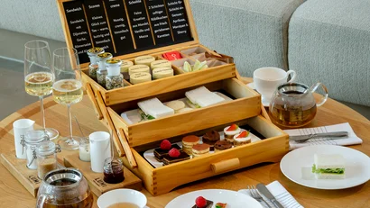 Tee-Set mit Gebäck, Sandwiches und Gläsern auf einem Holz-Tisch