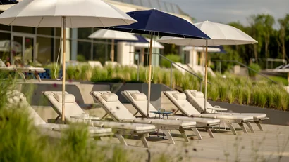 Leere Liegestühle mit Sonnenschirmen an einem sonnigen Poolbereich