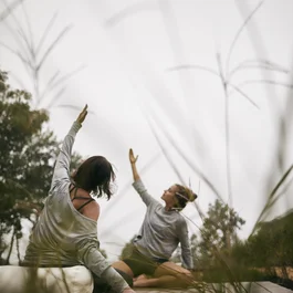 Zwei Frauen praktizieren Yoga im Freien auf einer Holzplattform